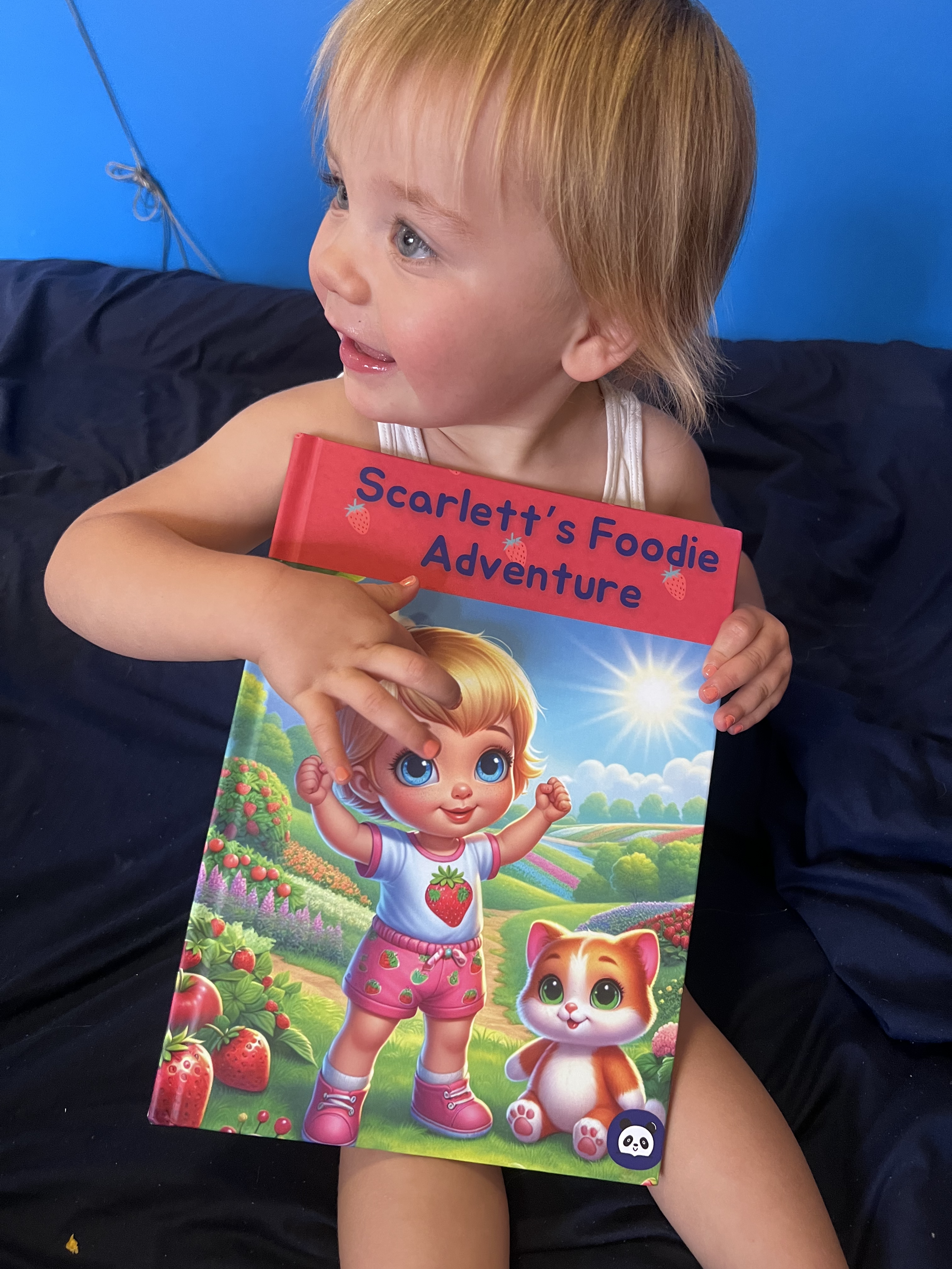 A child smiling whilst reading a storybook